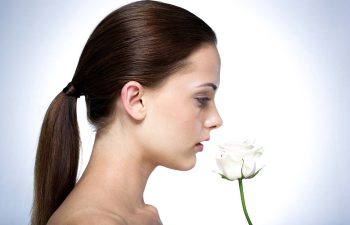 Woman smelling a white flower.